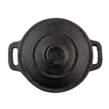 A round, black TableCraft cast iron mini casserole dish with a lid, seen from above on a white background. The pot features two rectangular handles and a raised circular knob, with a textured, slightly worn surface.