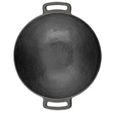 A round, black cast iron pan with a textured surface is seen from above. It features two sturdy handles with oval openings and appears well-seasoned. This induction ready pan rests on a white background.