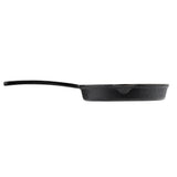 A black TableCraft cast iron skillet is seen from the side, showing its thick, textured body and a long, straight handle. The skillet sits on a white background, with its interior not visible from this angle.