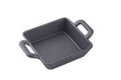 A small, square TableCraft CW30150 mini cast iron server with two short handles sits on a white background. The empty square mini server features a slightly textured black surface and classic cast iron design.