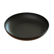 A round, shallow, black ceramic pasta bowl with a subtly textured surface and a slight rim, shown against a white background. The plate has a matte finish and a minimalist, modern design.
