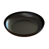 A round, shallow Pasta Bowl with a smooth, matte black finish and tiny white speckles covers its surface like a starry night sky. Crafted from cast aluminum, it’s photographed against a white background.