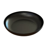A black, round, shallow plate with a matte finish and subtle white speckles, crafted from cast aluminum. The plate has a slight rim and a smooth, clean surface—durable and dishwasher safe for everyday use.