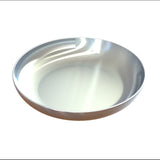 A shiny, empty cast aluminum pasta bowl with smooth, rounded edges sits on a plain white background. The surface displays subtle highlights and reflections, emphasizing its metallic texture and clean, dishwasher safe appearance.