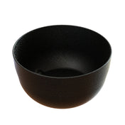 A black, round cast aluminum bowl with a matte, slightly textured finish is shown against a white background. The inside is smooth and dark, making it ideal as a fruit bowl with a wide opening and gently curving sides.