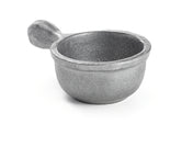 A small, round, silver-colored metal scoop with a short, thick handle. Crafted from cast aluminum with a rough, textured finish, it sits on a white background, casting a faint shadow beneath it. Dishwasher safe for easy cleaning.
