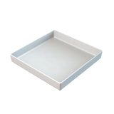 A plain, white, square tray with raised edges is shown against a white background. Reminiscent of a cold holding bowl, the tray features a smooth, glossy surface and is pictured at an angle showing the inside and two sides.
