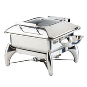 A shiny stainless steel chafing dish with a clear, hinged lid, elevated on four curved legs. A small replacement spoon rest is attached to one side, and a fuel holder beneath the dish keeps food warm for serving.