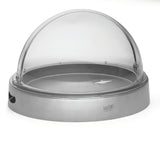 A round cold server with a stainless steel base and a clear polycarbonate dome lid. The tray features a small handle on top for easy lifting, a side cutout, and the TableCraft brand visible on the front.
