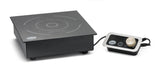 A sleek black single burner induction cooktop with white circular markings is displayed on a countertop. To the right, a separate control panel with a gold knob connects by cable. Both devices rest on a white background.