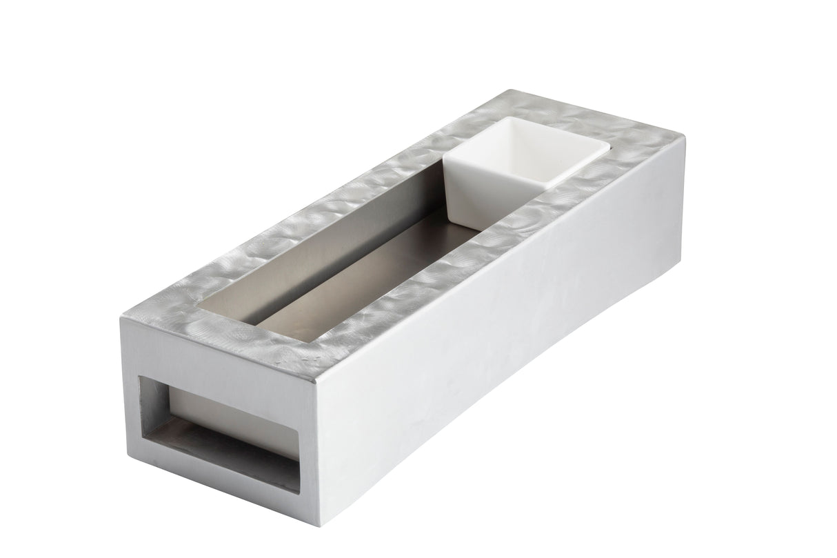 A modern, rectangular metallic object with a slightly textured surface, featuring a recessed channel in the center and a small white square bowl at one end—perfect as a TableCraft cooling station thanks to its open section.
