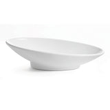 A white, shallow, oval-shaped Sierra Collection Bowl with a small round base is shown on a plain white background. The bowl is angled, displaying its smooth, minimalist design and clean lines.