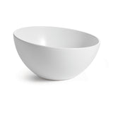 A white, round Sierra Collection Bowl with smooth, clean lines sits on a white surface. The bowl is empty and angled slightly to the left, casting a faint shadow on the right. A plain, bright background emphasizes the bowl’s shape and simplicity.