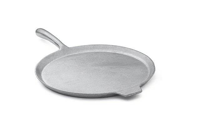A flat, round, silver cast aluminum pizza pan with a slightly raised edge, a long curved handle on one side, and a small helper tab on the opposite side. The smooth surface appears against a plain white background.