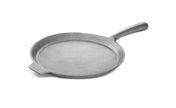 A round, flat, cast iron griddle with a shallow lip and a long handle on one side. This gray, uncoated pizza pan has a small pouring spout opposite the handle and is set against a white background.