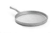 A silver-colored, round cast aluminum frying pan with a textured surface and a short handle, photographed on a white background. The pan appears empty and its slightly raised edge is visible.