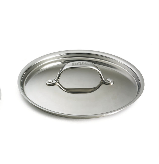 A shiny, stainless steel lid with a curved handle attached by two rivets sits on a white background. The highly reflective, oval-shaped lid is dishwasher safe and has the All-Clad brand engraved on the handle’s arch.