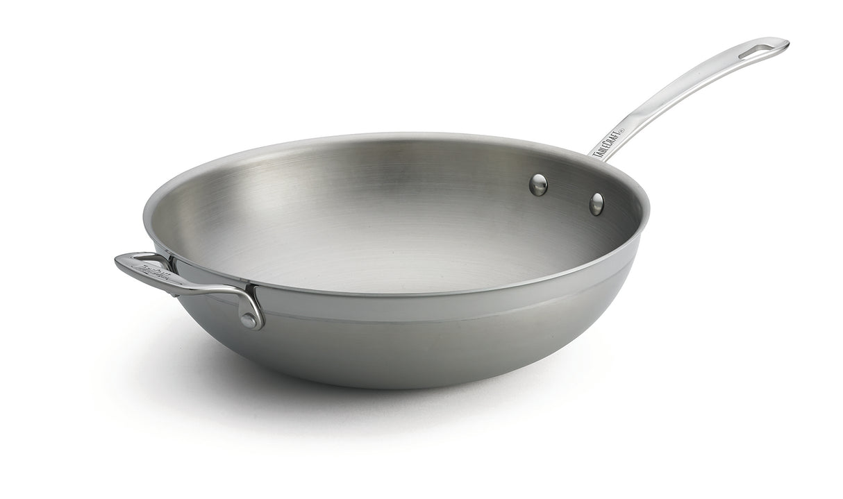 A tri-ply wok with a shiny stainless steel finish, featuring a wide, rounded base and tall sides. It includes a long handle and a riveted helper handle for stability—plus, this dishwasher safe wok is set against a white background.
