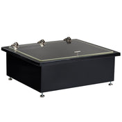 A black, rectangular laboratory glove box with a sleek black brushed finish and an acrylic lid secured by three metal latches. It sits on four adjustable metal feet and features a front handle for easy opening, emphasizing its modern, industrial appeal.