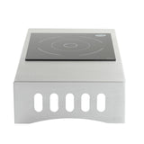 The Induction Station by TableCraft Products is a single burner cooktop with a stainless steel body, flat black glass surface featuring white concentric circles, and a rounded front with vertical ventilation slits for a sleek finish.
