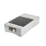 A rectangular stainless steel Induction Station from TableCraft Products, featuring a single burner with circular markings on a black glass surface and a control knob on the front panel. The cooktop rests on a white background.