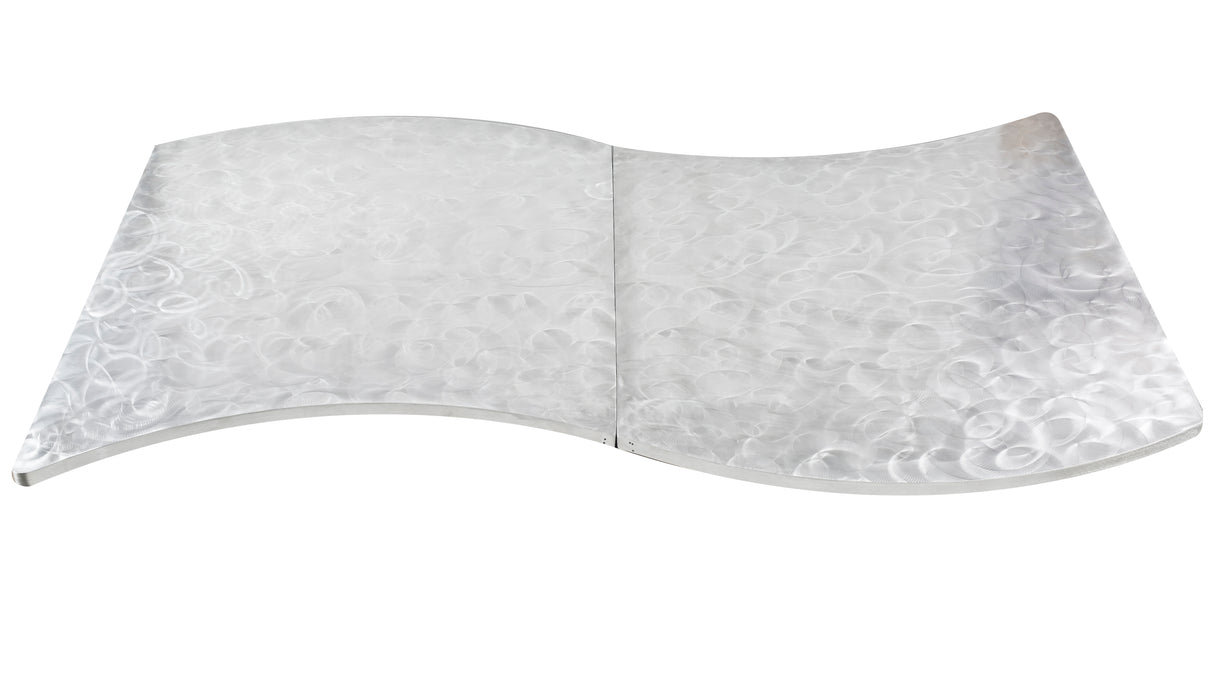 A flat, metallic sheet with a smooth, reflective surface and a wavy, S-shaped curve resembles an elegant serpentine table cover. Its circular, textured pattern catches the light for a shimmering effect against the white background.