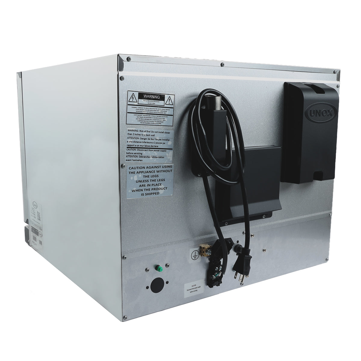 A large silver industrial convection oven with a black Unox-branded soap or sanitizer dispenser mounted on its side, a coiled electrical cord, warning labels, control buttons, and indicator lights on the metal panel. The background is white.