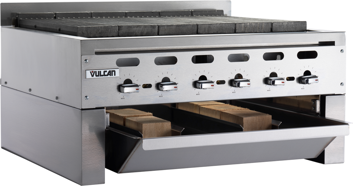 A commercial stainless steel Vulcan charbroiler with four control knobs, grates on top, and a front drawer partially open showing several wooden planks inside. The clean, sturdy design features a Wood Assist Achiever Smoker Base for professional kitchens.