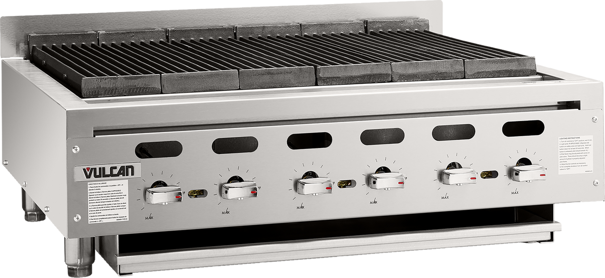 The Vulcan VACB36 Achiever Charbroiler is a stainless steel countertop charbroiler with six control knobs, ventilation holes, a metal grate top for grilling, and safety labels on the front panel. It stands on four short legs for stability.
