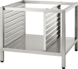 A stainless steel Deluxe Stand with four legs, horizontal support bars, and side panels featuring parallel slats. The flat solid base offers pan supports, creating a sturdy and industrial design ideal for holding 102 TCM units or appliances.