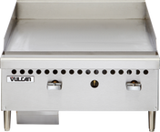 The Vulcan VCRG24-M is a stainless steel 24" countertop gas griddle with two control knobs, smooth flat-top surface, short metal legs, small ventilation holes above the knobs, and a grease tray underneath on the left side.
