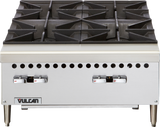A stainless steel commercial gas hotplate stove with four large black cast iron burners, sturdy control knobs at the front, ventilation holes above the knobs, and the Vulcan brand logo in the lower left corner. The stove stands on four metal legs.