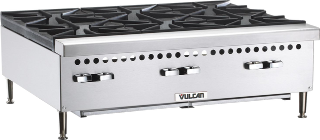 A commercial stainless steel Vulcan VCRH36 gas countertop hotplate featuring four large black cast iron open burners, four metallic control knobs on the front panel, and the “Vulcan” name at the bottom center. The unit stands on four sturdy metal legs.