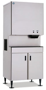 A large, industrial stainless steel ice machine with a boxy upper section for making ice and a lower cabinet with two doors for storage; the machine stands on an equipment stand with four sturdy black legs.