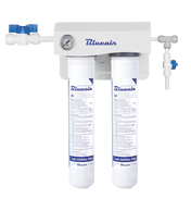 A Blueair dual filtration system mounted on a wall, featuring two vertical cylindrical filters with labels, a small pressure gauge, pipes, and a blue valve. The setup ensures scale reduction, ideal for use as an ice machine water filter.