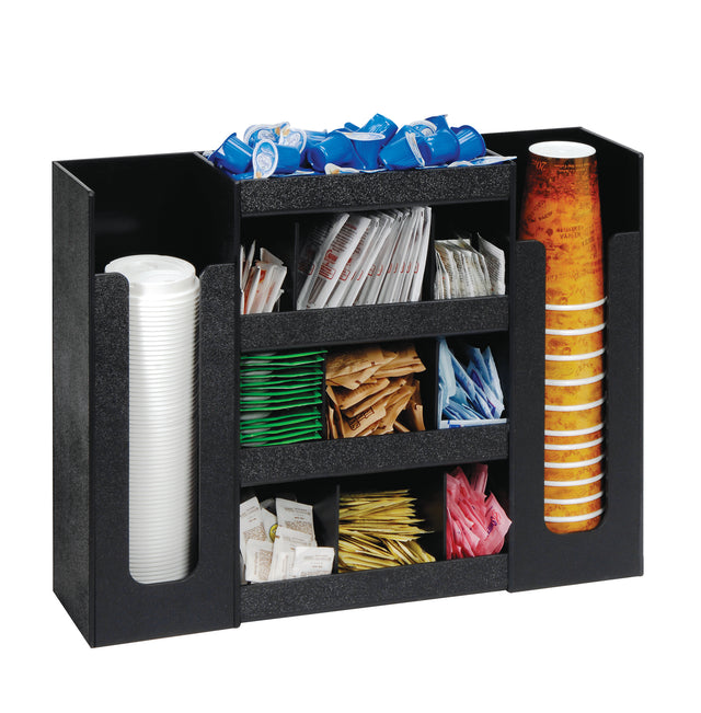 A black condiment organizer holds stacks of disposable cups on both sides, with coffee creamers, cup lids, and assorted sugar packets neatly arranged in the middle compartments—perfect for a streamlined Dispense-Rite setup.
