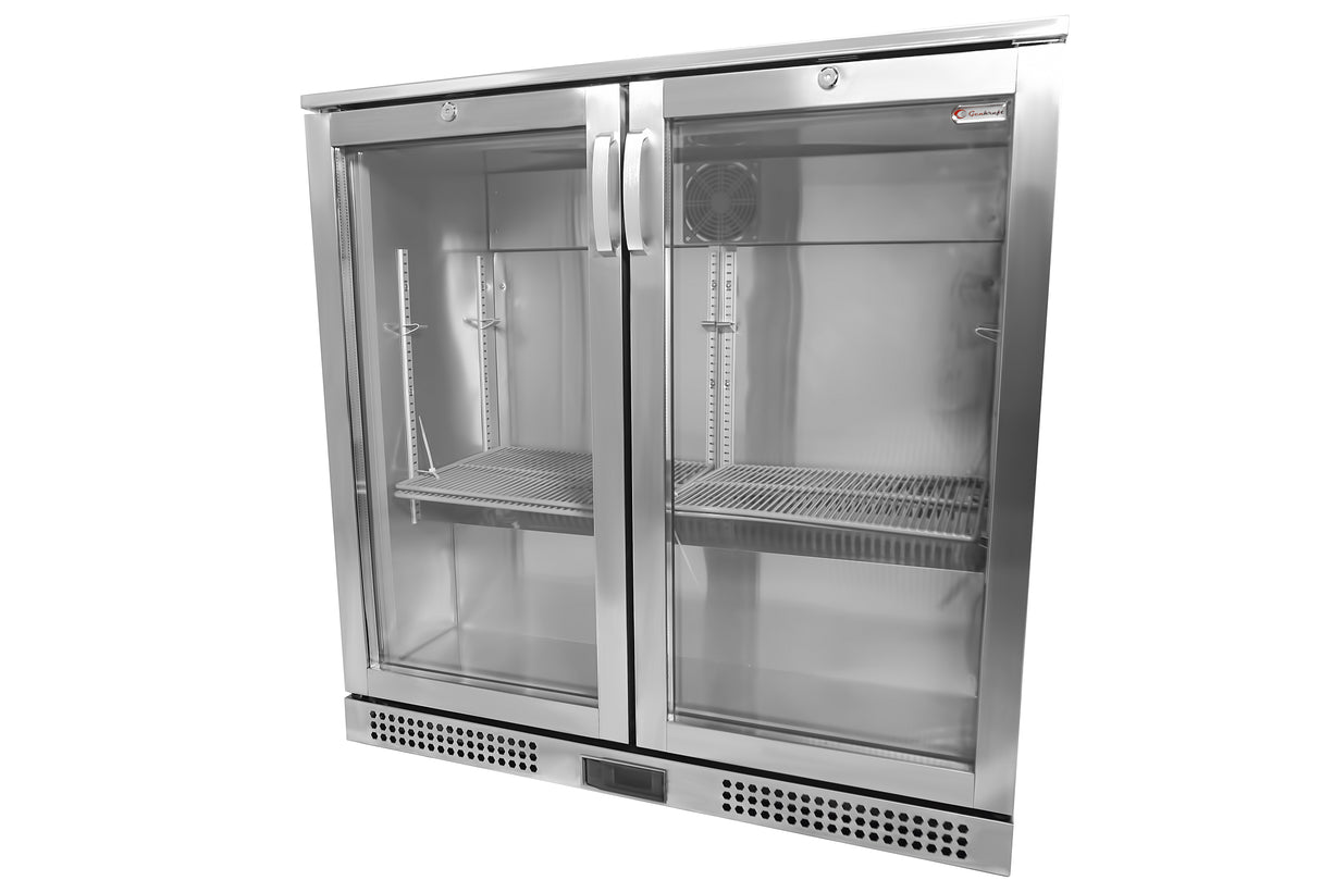 A commercial glass door cooler with stainless steel construction, two vertical handles, wire shelves, and a visible cooling fan inside. This Refrigerated Back Bar Cooler has a vented base and a digital display at the bottom center. The interior is empty.