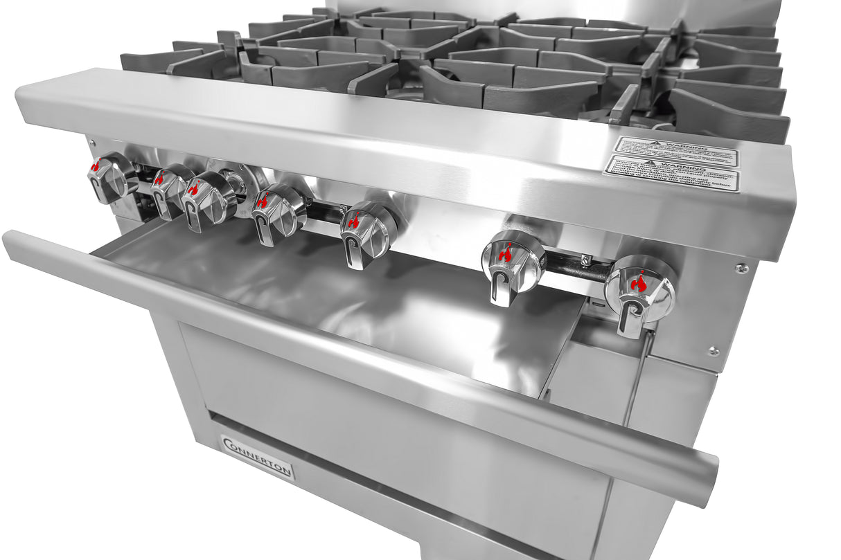 A close-up of a commercial stainless steel restaurant range with six gas burner knobs, each marked by a red flame icon, and heavy-duty cast iron grates. The Bake-n-Roast oven compartment is located just below the burners.
