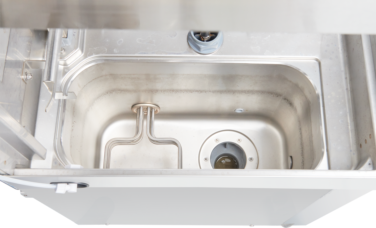 A top-down view of a stainless steel commercial dishwasher interior, showing a rectangular wash basin with a metal heating element and circular drain. The surfaces appear clean, and there are no dishes present in this door type dishwasher.