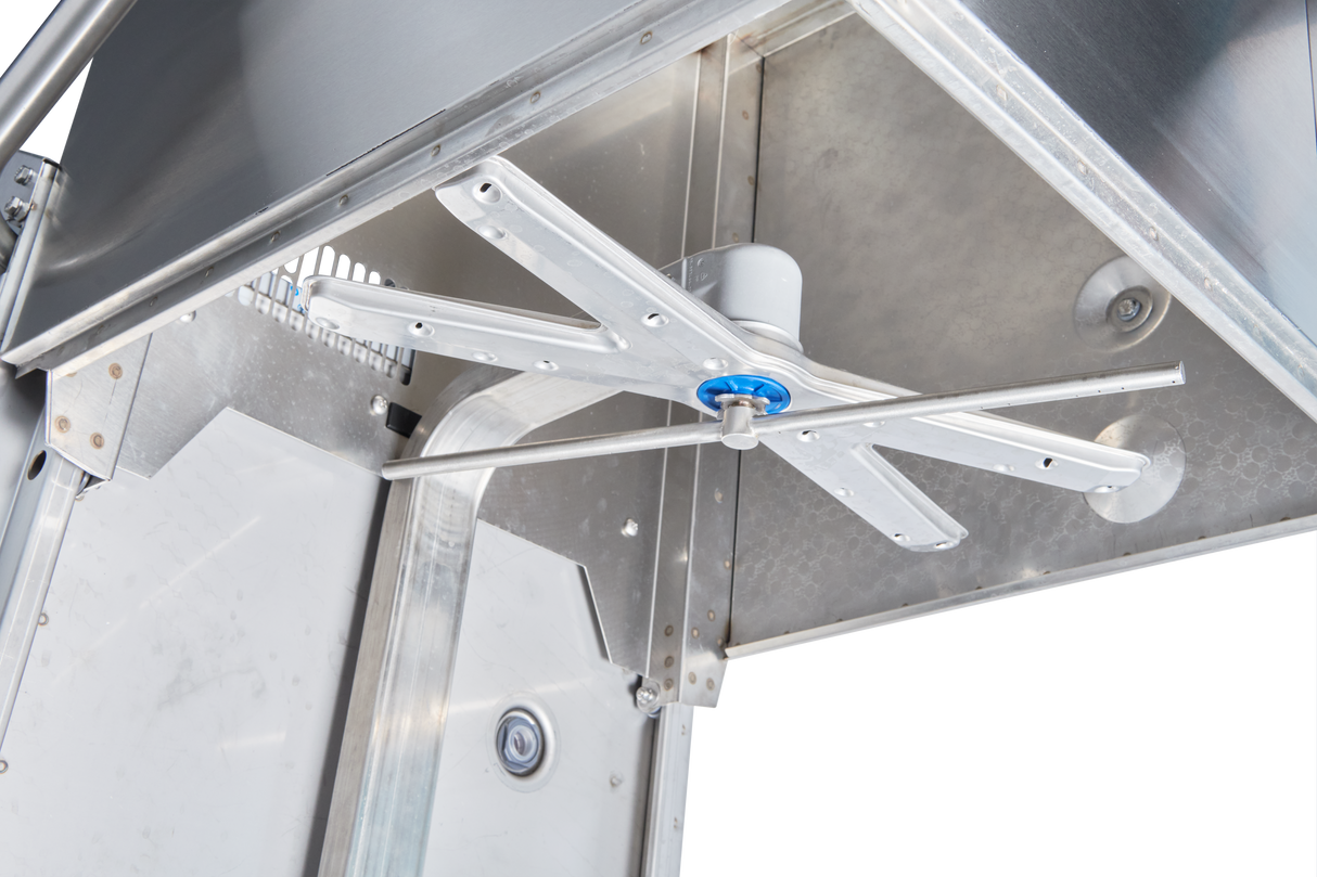 Close-up view of the interior of a stainless steel commercial dishwasher, showing a metal rotating spray arm with multiple nozzles. The arm is mounted to the machine ceiling, surrounded by smooth metallic panels and visible bolts.