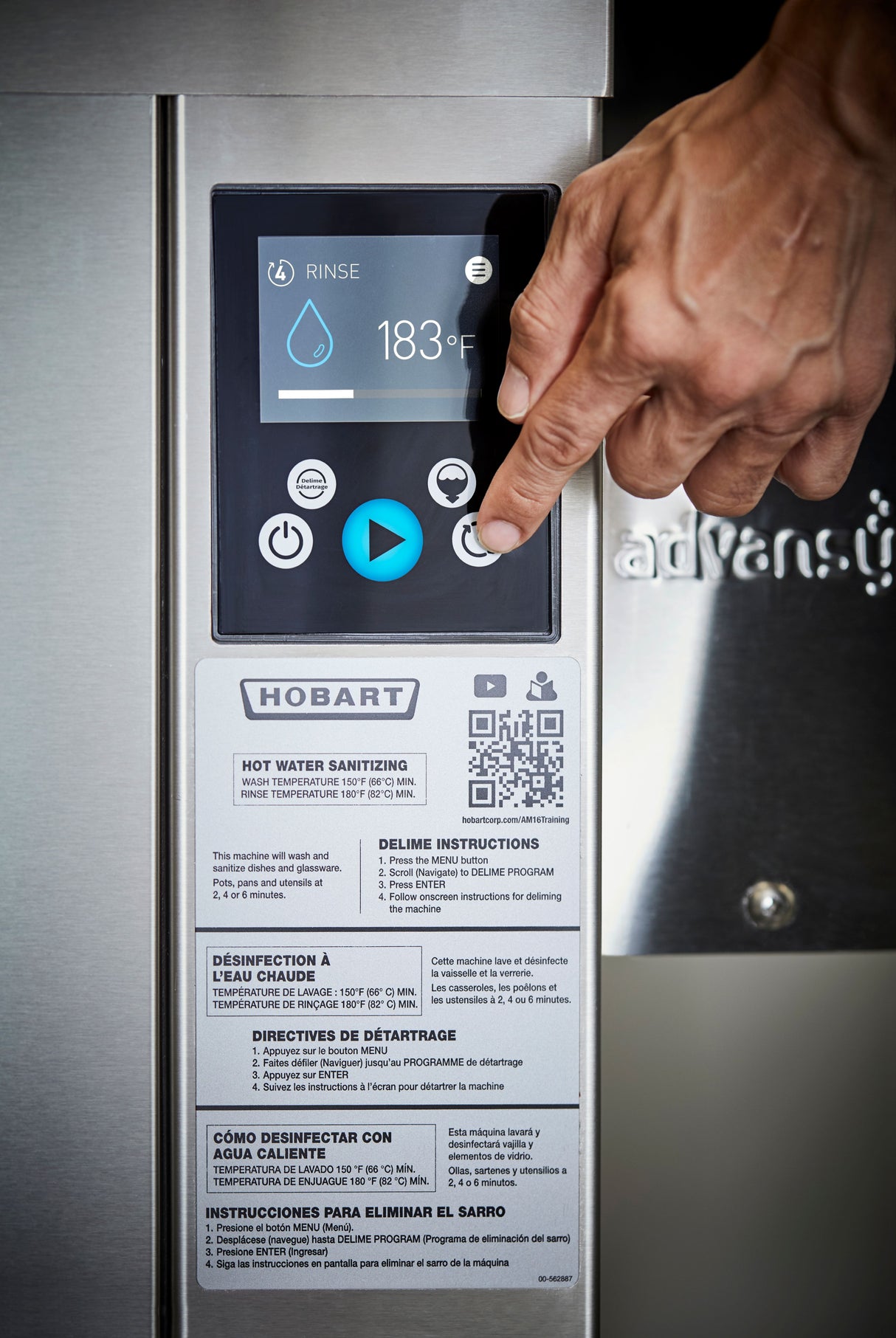 A hand presses a button on a Hobart ventless dishwashing machine’s digital touch screen, which displays a water droplet icon, “RINSE,” 183°F for high temp sanitizing, with control buttons, instruction labels, and a QR code in multiple languages below.