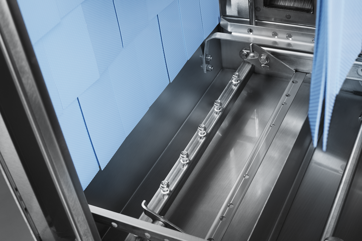 Close-up of a metallic industrial machine interior with a horizontal spray bar featuring multiple nozzles, ideal for automatic soil removal in conveyor dishwashers. Blue textured panels line the stainless steel construction, highlighting clean precision.