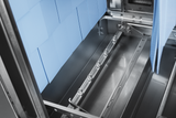 Close-up of a metallic industrial machine interior with a horizontal spray bar featuring multiple nozzles, ideal for automatic soil removal in conveyor dishwashers. Blue textured panels line the stainless steel construction, highlighting clean precision.