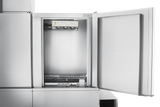 A stainless steel ice maker with its door open reveals the inner compartment and ice-making mechanism at the top, reminiscent of a conveyor dishwashers clean, modern design. The metallic exterior and interior are spotless against a white background.