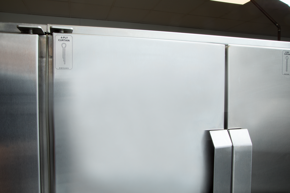 A close-up of large stainless steel commercial refrigerator doors, reflecting light in a clean, industrial kitchen setting. Next to a Hobart FT1000E low energy flight type dish machine, the doors feature vertical handles and a “PULLY CURTAIN” sign.