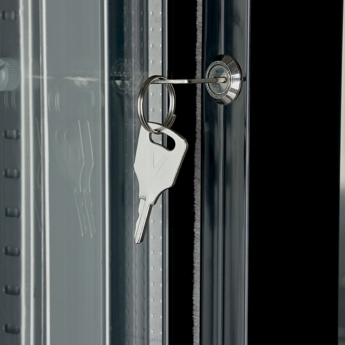 A silver key is inserted into a lock on an Empura refrigeration back bar cooler with sliding glass doors. The key, attached to a metal ring, reflects clearly on the glass beside the sleek black door frame.