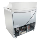 A stainless steel Empura refrigeration salad prep table is shown from the back. Its lower panel is open, revealing wiring, a black compressor, and metal grates. The refrigerated sandwich prep table rests on small wheels for easy mobility.