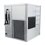 A rectangular, silver commercial ice maker with a vented front panel, black coiled power cord on the side, warning labels, and instructions on the right. The unit stands on four short feet and features a large grill and small ventilation grate.