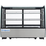 A stainless steel Empura refrigerated display case with glass front and sides, featuring two wire shelves and interior LED lighting. This countertop display case is empty, with the Empura logo visible on the bottom left corner.