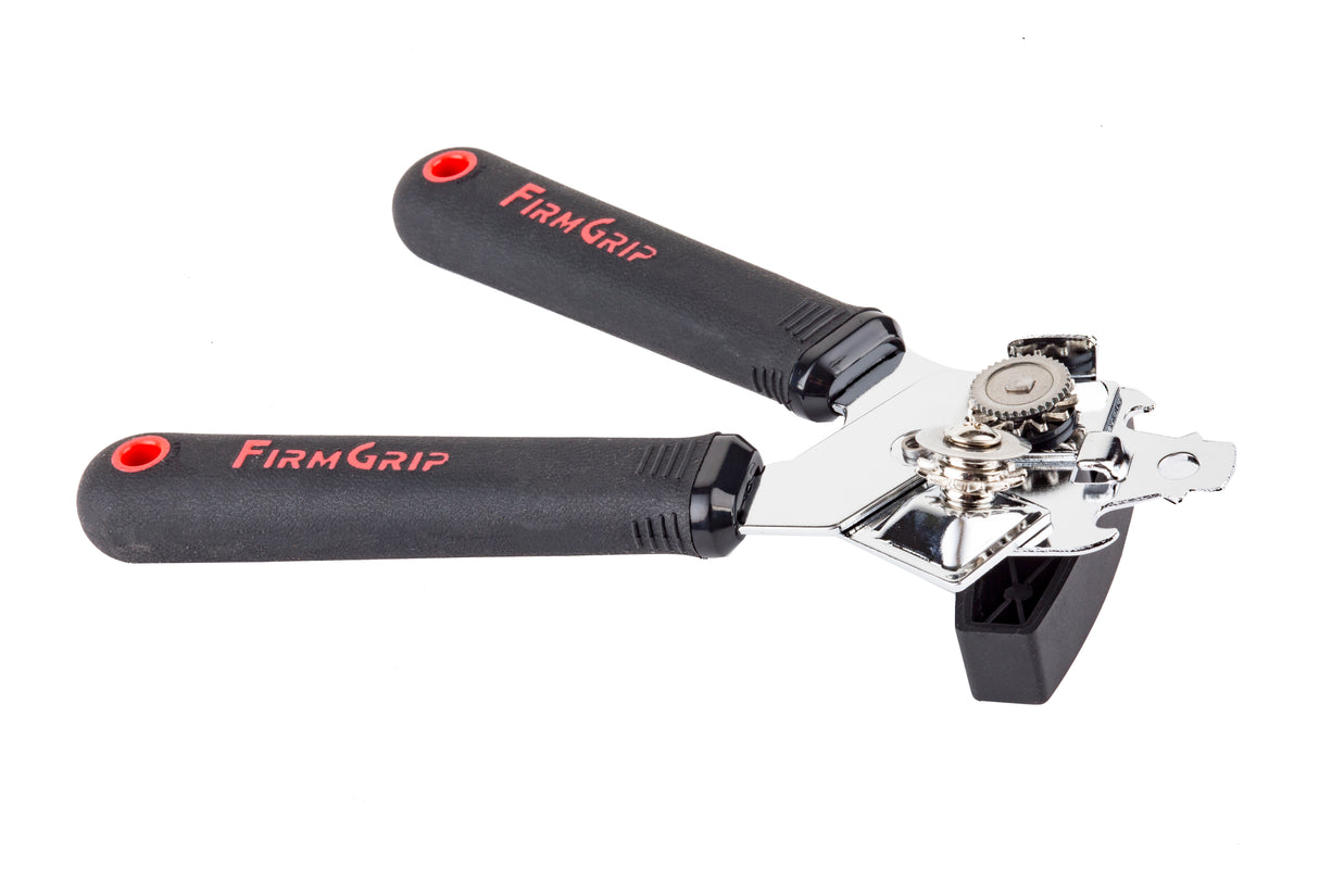 A FirmGrip Hand Can Opener with black, textured ergonomic handles labeled “FIRM GRIP” in red. The handles have red circular accents, while the cutting mechanism and gears are shiny stainless steel, and the turning knob is black plastic.